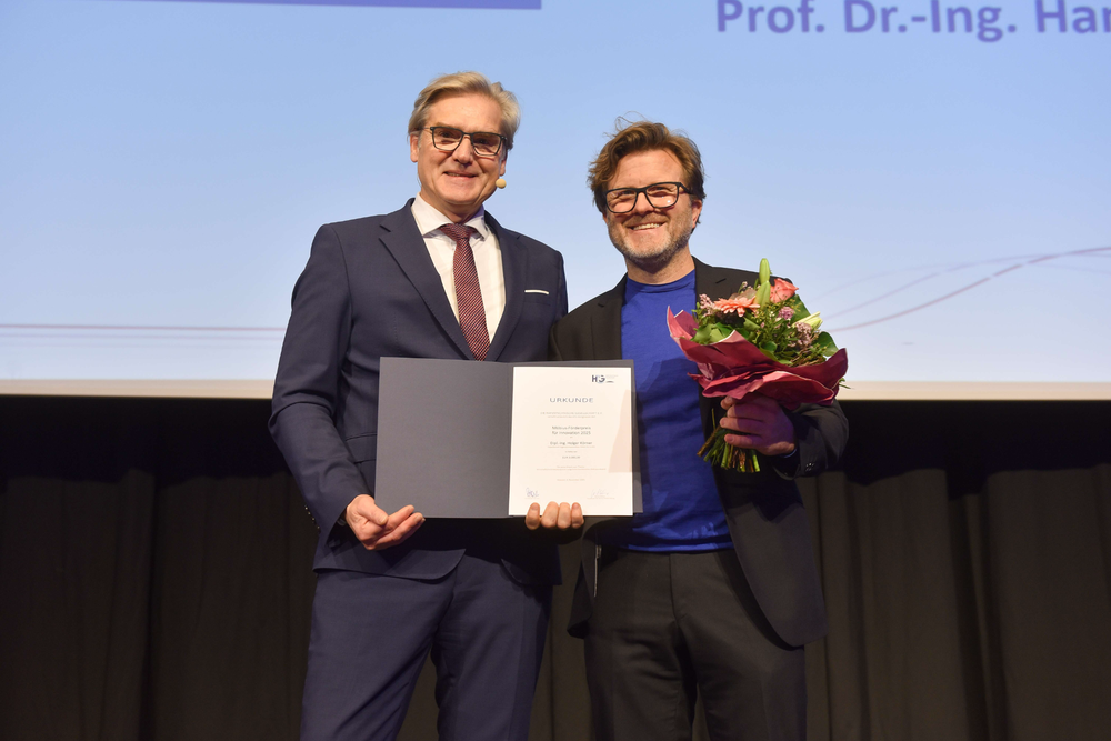 Eine Siegerehrung mit einem Sieger und einem Verleiher des Preises