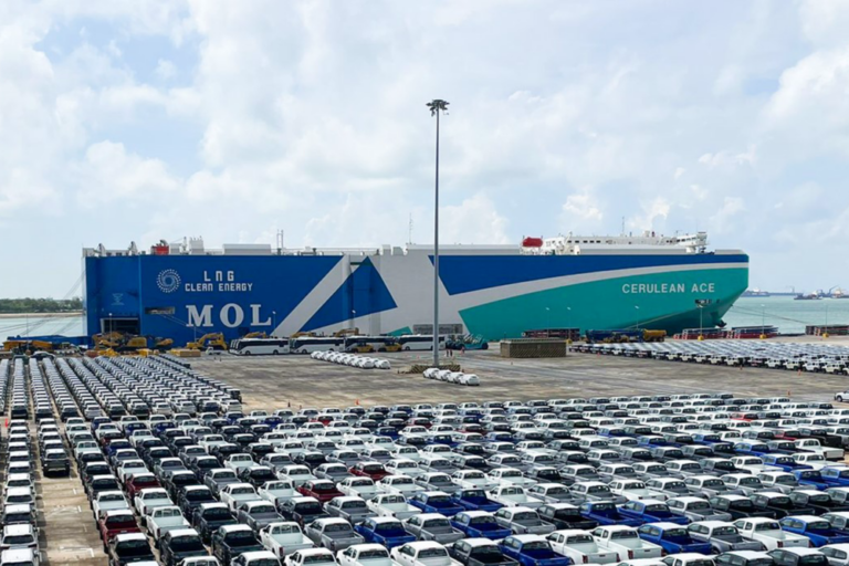 Ein Autocarrier von MOL im Hafen. Im Vordergrund stehen Neuwagen.