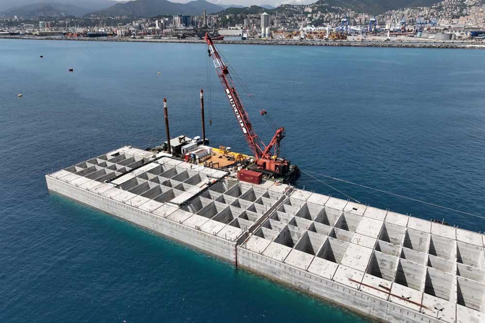 Blick auf den Hafen von Genua, im Vordergrund ein Kran auf einem Betonelement im Meer