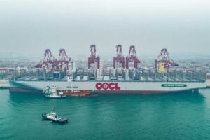 Containerschiff und Bunkerschiff vor Hafenkranen in Qingdao
