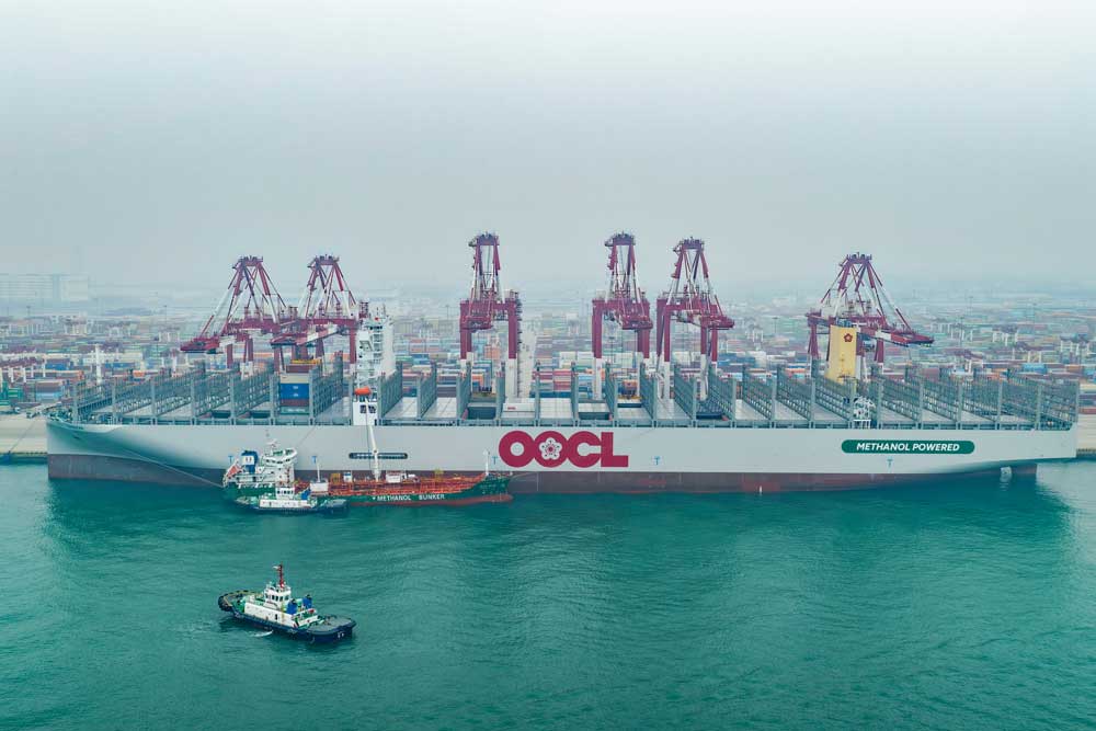 Containerschiff und Bunkerschiff vor Hafenkranen in Qingdao