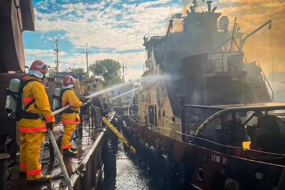 Feuerwehrleute löschen einen brennenden Schlepper